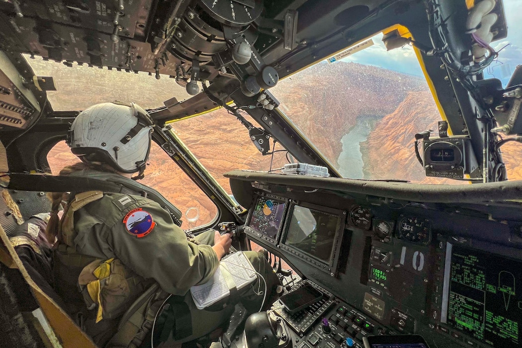 A sailor turns left while sitting in a cockpit while flying over the Grand Canyon.