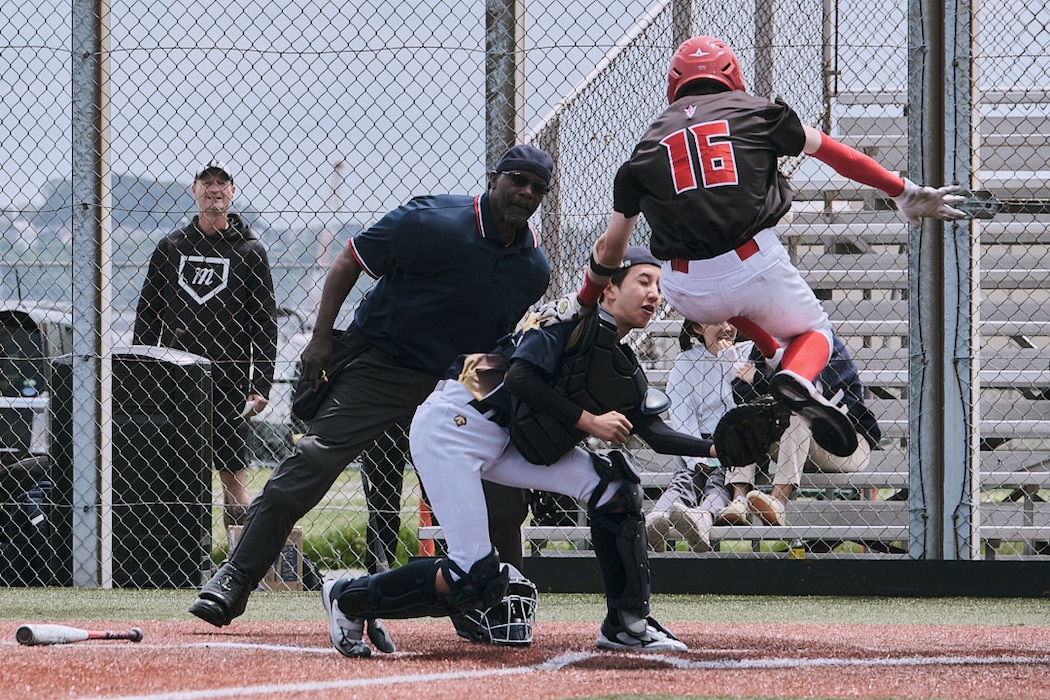 A baseball player from Nile C. Kinnick High School tries to score by jumping over a catcher during a high school baseball game in Yokosuka, Japan.
