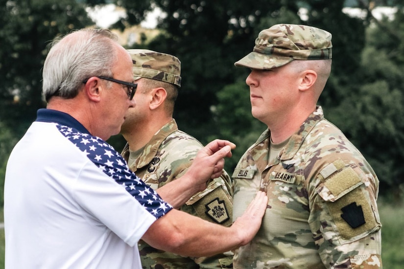 A civilian pins a rank on a soldier.