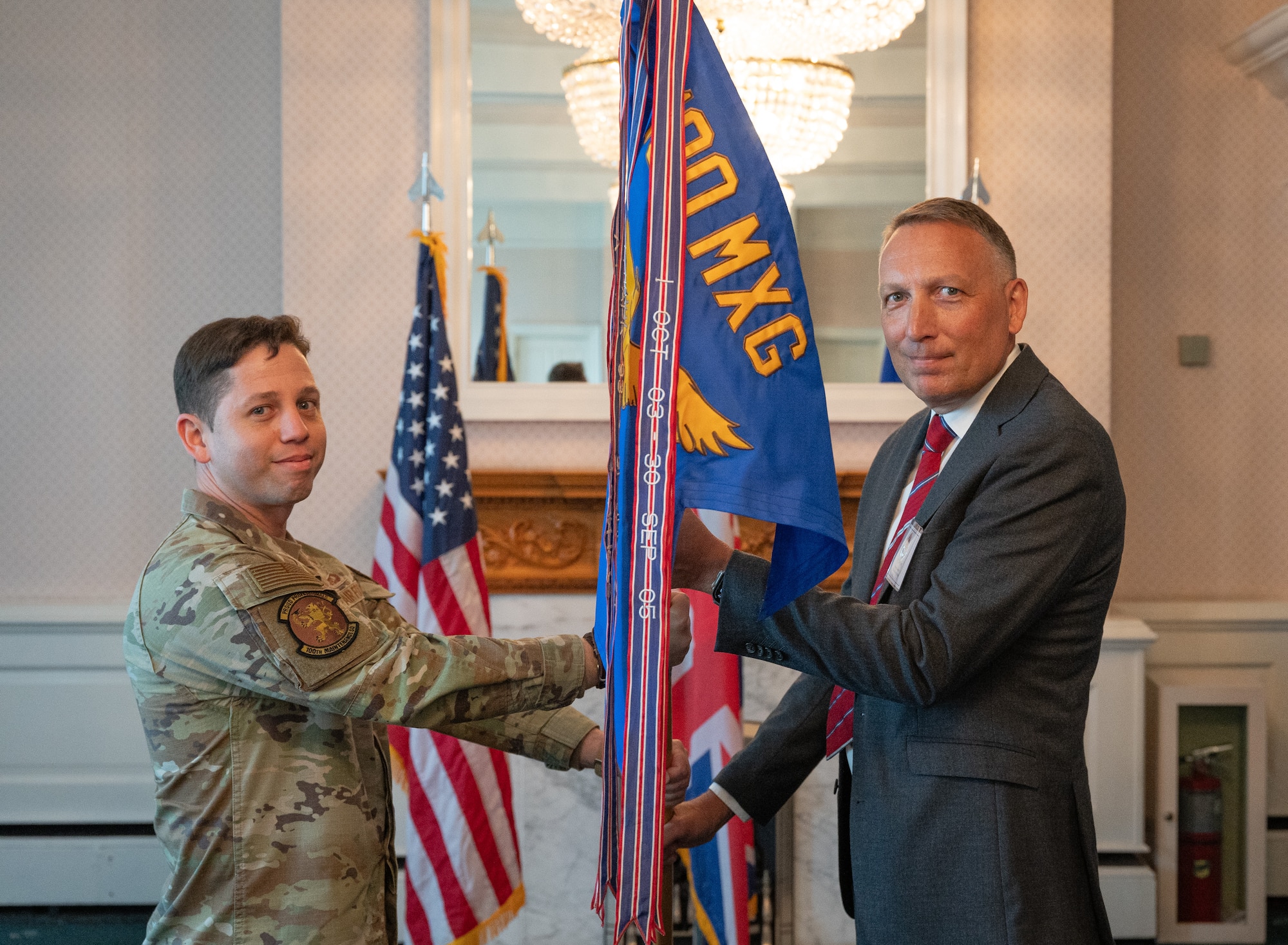 U.S. Air Force Lt. Col. Emilio Rodriguez, left, 100th Maintenance Squadron commander, passes the 100th MXS guidon to Julian Long, Electronic Metalwork Services managing director,  during the honorary commanders’ induction ceremony at Royal Air Force Mildenhall, England, April 24, 2024.