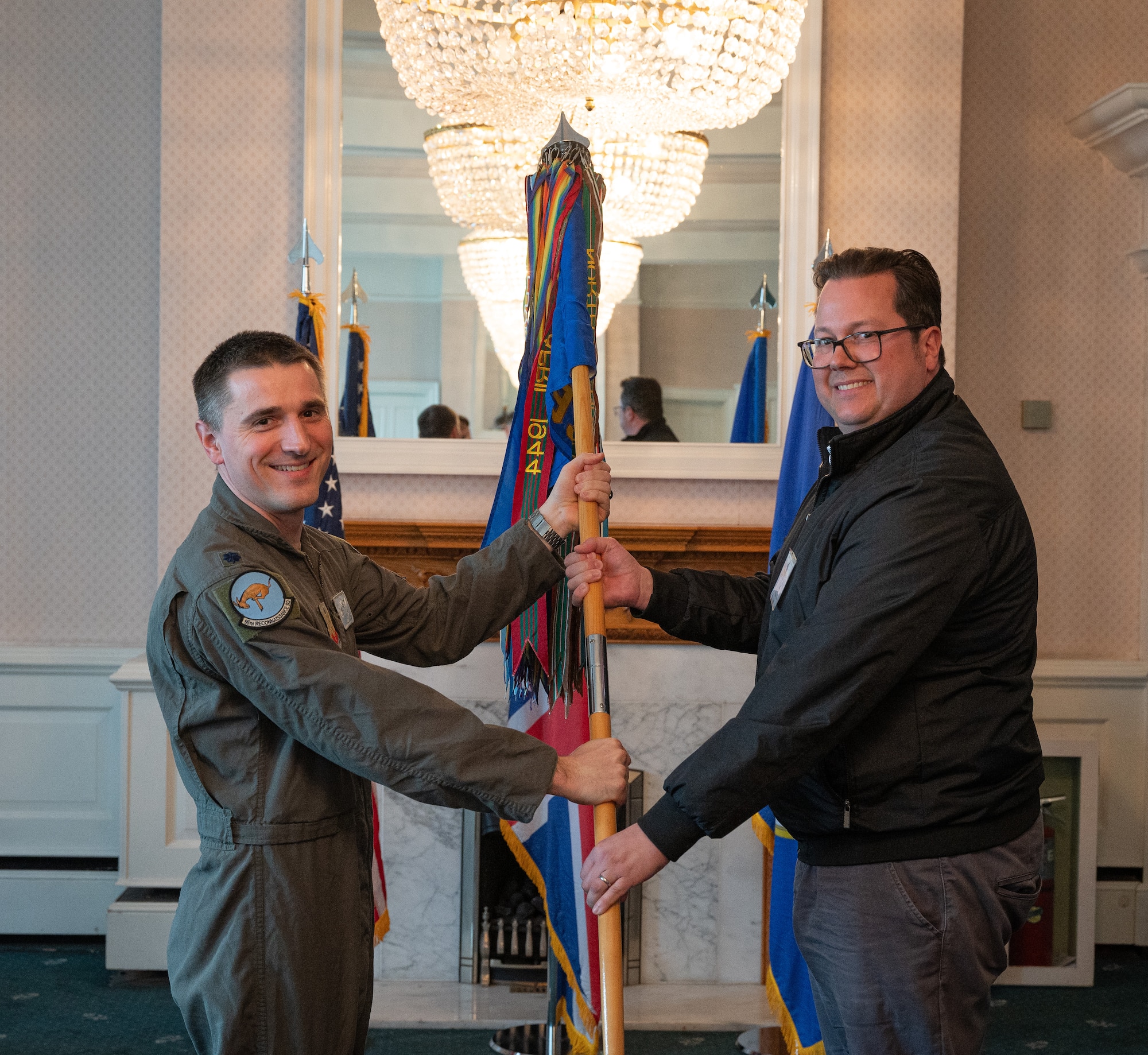U.S. Air Force Lt. Col. Elliot Kipp, left, 95th Reconnaissance Squadron commander, passes the 95th RS guidon to Ian Brown, Royal Air Force Sculthorpe Heritage Centre curator, during the honorary commanders’ induction ceremony at RAF Mildenhall, England, April 24, 2024.
