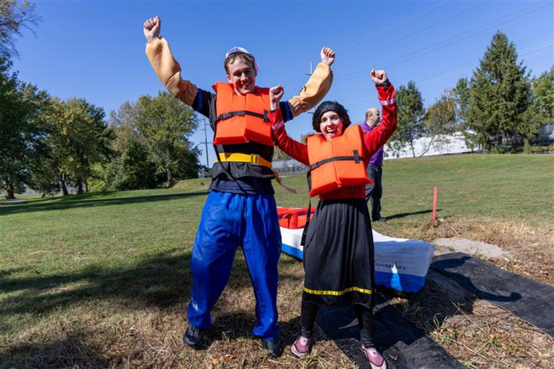 Two people dressed as Popeye and Olive Oyl smile and raise hands in celebration.