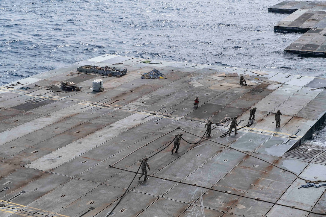 U.S. Army Soldiers assigned to the 7th Transportation Brigade (Expeditionary) handle line to secure the Roll-On, Roll-Off Distribution Facility (RRDF), or floating pier, to the side of the MV Roy P. Benavidez, in support of Joint Logistics Over-The-Shore (JLOTS) operations off the coast of Gaza, May 1, 2024. The temporary pier will assist the United States Agency for International Development in the delivery of humanitarian aid to the people of Gaza, which will increase the quantity and flow of humanitarian aid, including food, water, medicine, and temporary shelters. (U.S. Navy photo)