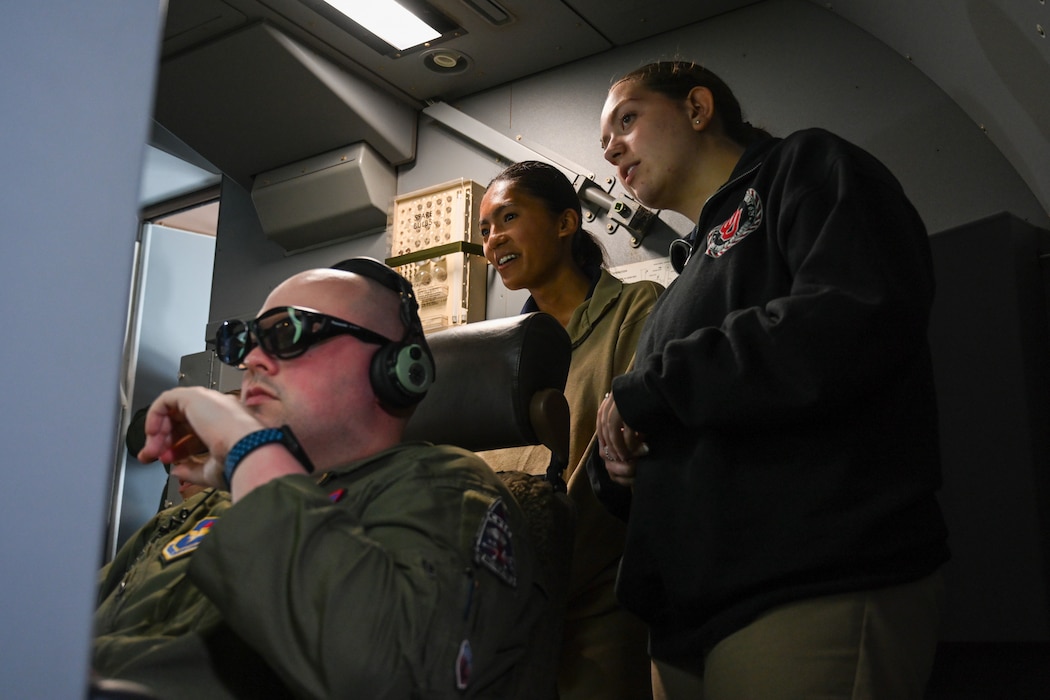 From the left, U.S. Air Force Staff Sgt. Carter Russell, 54th Air Refueling Squadron boom operator instructor, demonstrates air refueling to Cara Leyses, and Bradley Core, ROTC cadets, in the skies of Texas, April 25, 2024. Boom operators manage in-flight air refueling controls and switches to safely affect contact between aircraft. (U.S. Air Force photo by Airman Lauren Torres)