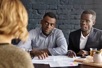 Unrecognizable Caucasian female being interviewed by doubtful future boss and HR director, who sitting at desk with papers in front of her, asking questions about job experience and personal qualities
