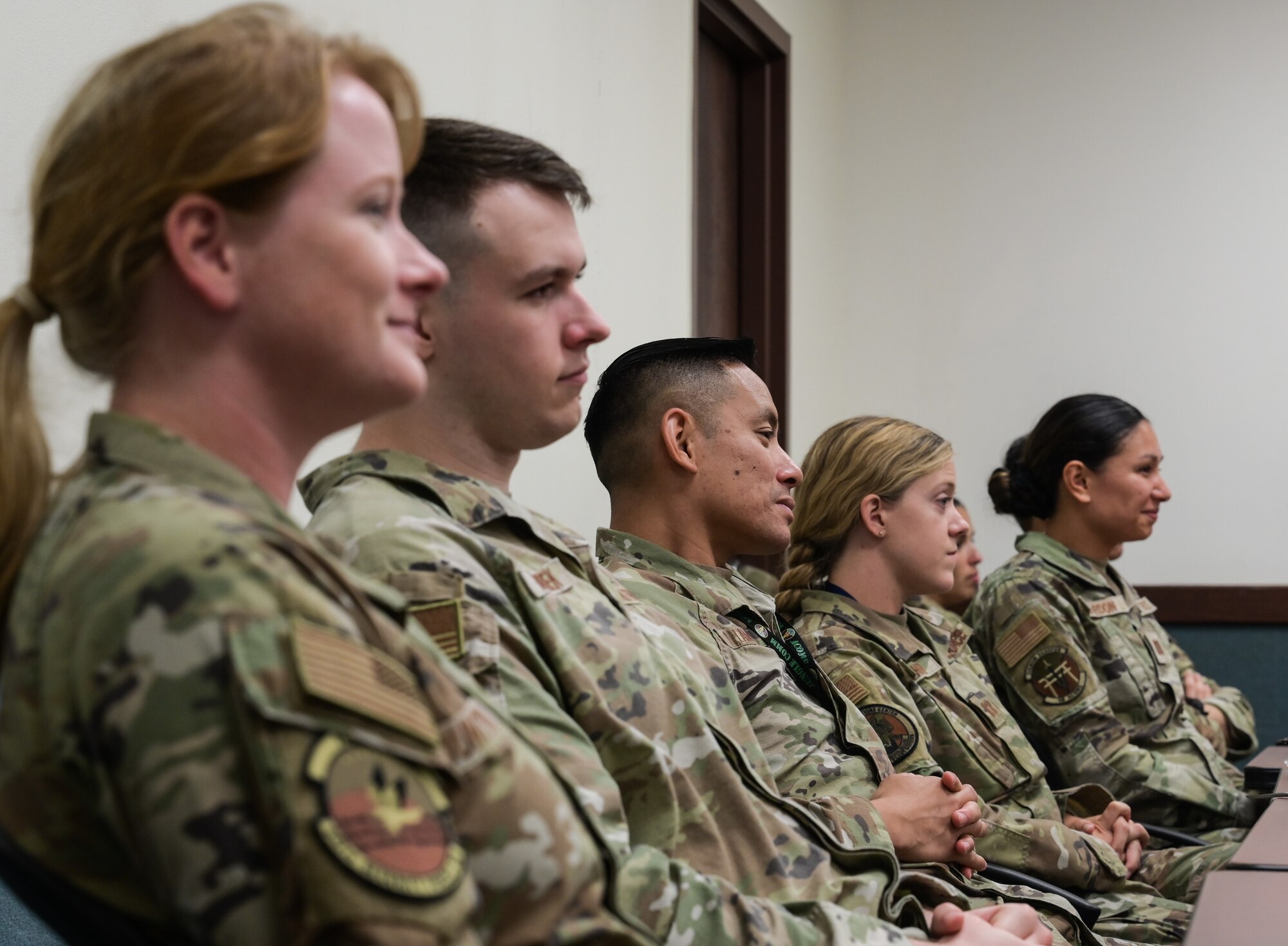 Airmen sit in a classroom.