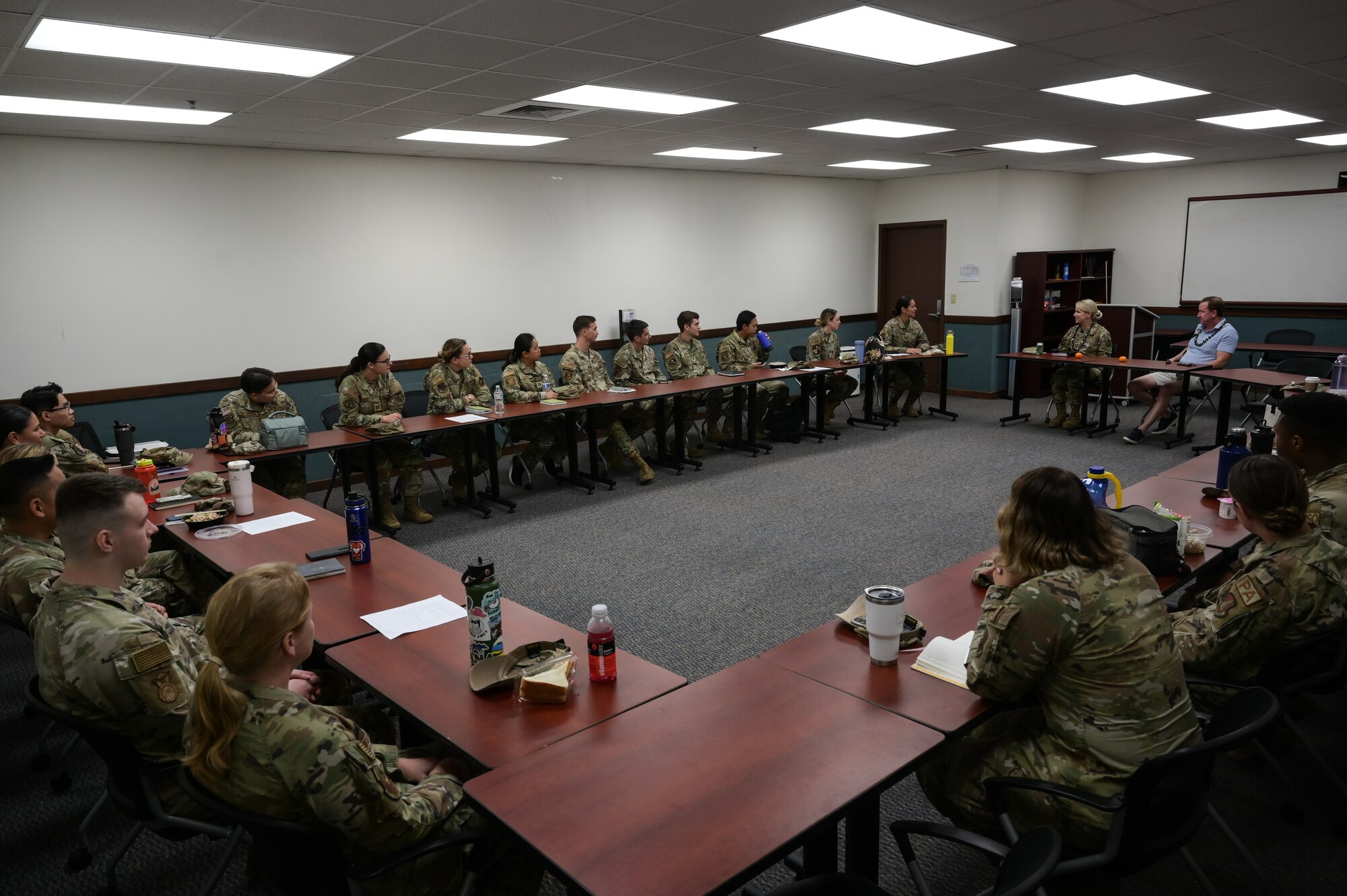 Airmen sit in a u-shaped table.