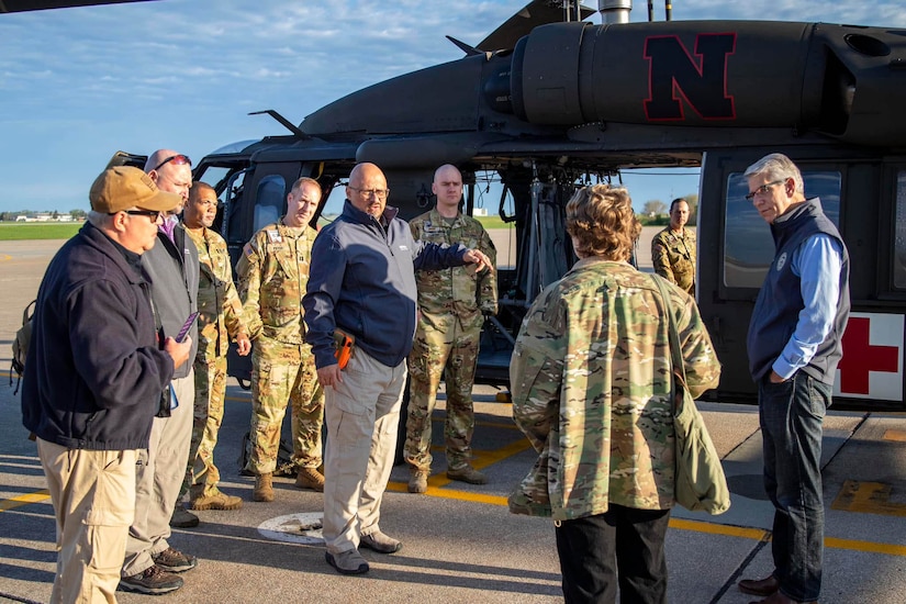 Nebraska civilian and military leaders stand next to a Black Hawk helicopter.