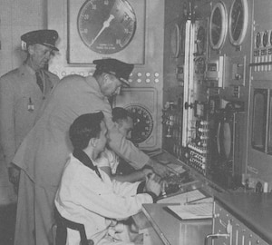 Gen. Thomas Power, then-commander of the Air Research and Development Command, center, punches the start button on May 3, 1954, to initiate the first turbojet engine test in the new Engine Test Facility at Arnold Air Force Base, Tenn., while Brig. Gen. Sam Harris, commander of what was then known as the Arnold Engineering Development Center, left, looks on. Not only did this begin the engine test in ETF, but it also represented the first simulated flight test of an engine at AEDC. Seated at the ETF control room console are test crewmen J.D. Higgenbottom, foreground, and I.F. Bailey. (U.S. Air Force photo)