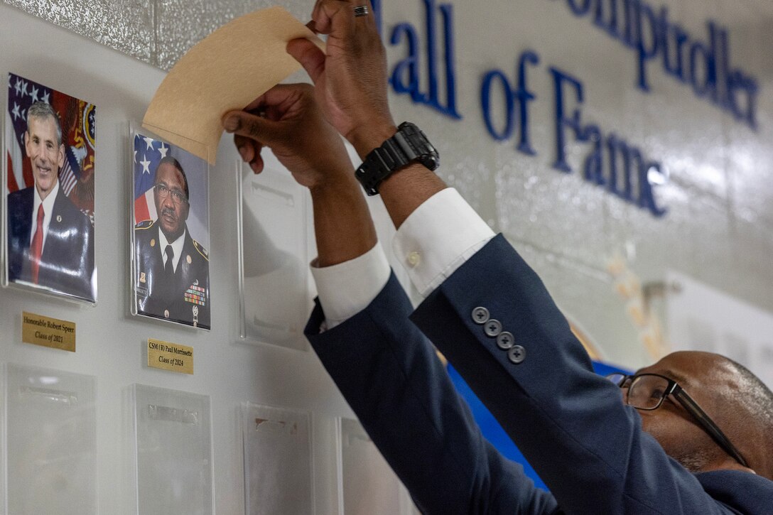 Retired Command Sgt. Maj. Genarro A. Penn, U.S. Army Financial Management Command Military Pay Operations supervisory financial systems analyst and former Finance Corps regimental sergeant major, unveils the official photo of retired Command Sgt. Maj. Paul L. Morrissette during a Finance and Comptroller Hall of Fame induction ceremony at the Soldier Support Institute on Fort Jackson, South Carolina, April 26, 2024. Morrissette, also a former Finance Corps regimental sergeant major, was made the third inductee of the hall of fame for his service and commitment to the U.S. Army Finance Corps for more than forty years. (U.S. Army photo by Mark R. W. Orders-Woempner)