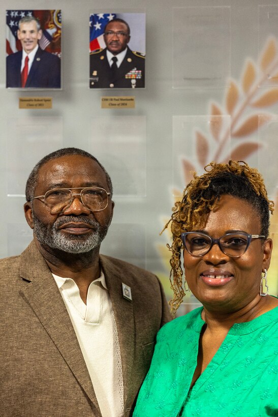 Retired Command Sgt. Maj. Paul L. Morrissette and his wife Renee Warren-Morrissette pose for a photo under a newly unveiled portrait of Morrissette on the Finance and Comptroller Hall of Fame Wall during an induction ceremony at the Soldier Support Institute on Fort Jackson, South Carolina, April 26, 2024. Morrissette, a former Finance Corps regimental sergeant major, was made the third inductee of the hall of fame for his service and commitment to the U.S. Army Finance Corps for more than forty years. (U.S. Army photo by Mark R. W. Orders-Woempner)