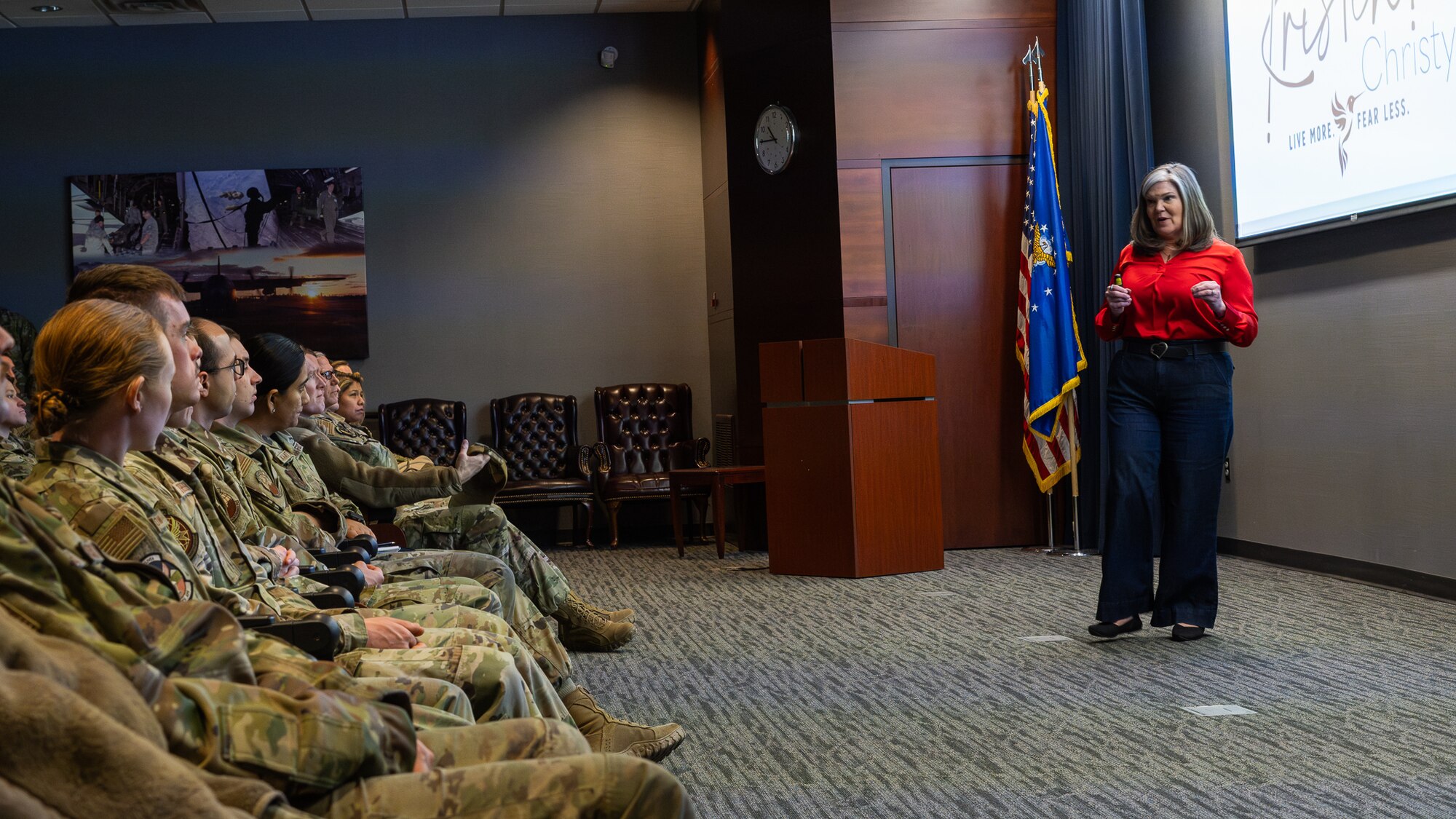A woman speaks in front of a crowd of uniformed military personnel.