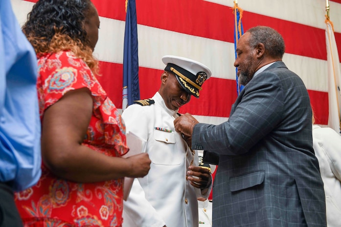 Three people stand on stage.