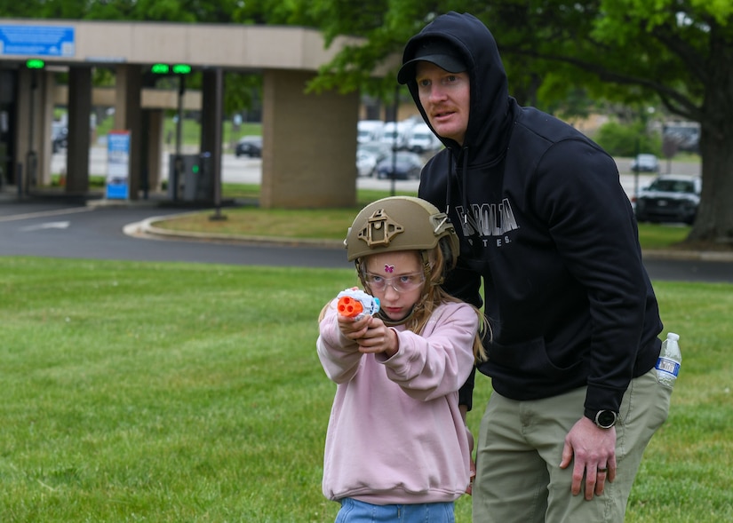 Father helps daughter on mock marksman activity.