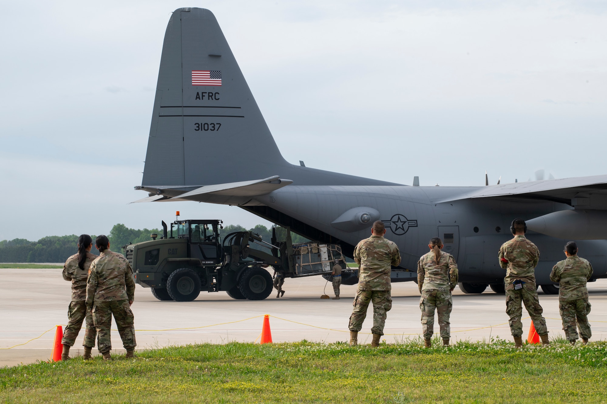 people in military uniforms look at an airplane