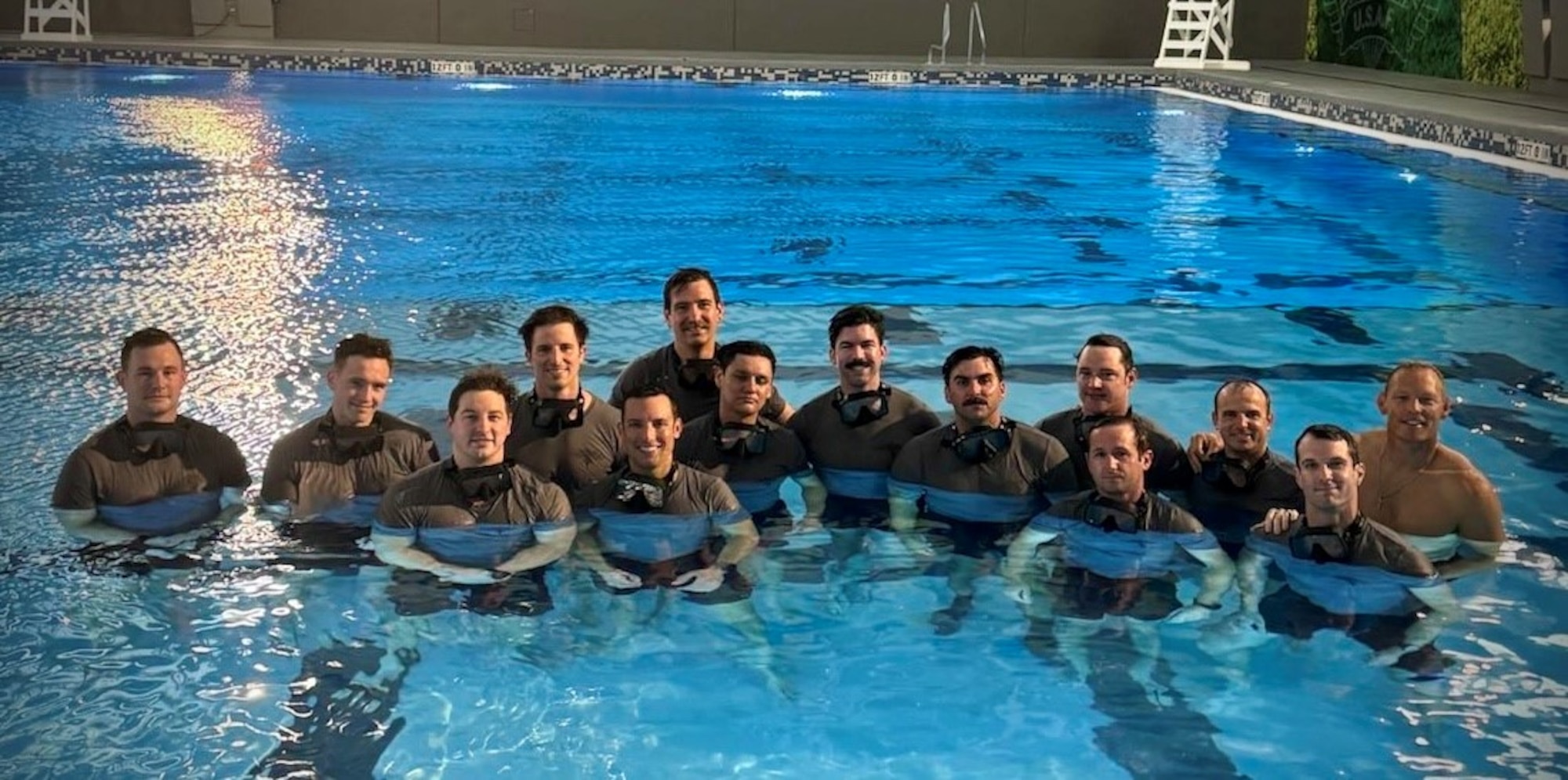 A group of Special Warfare instructors pose for a picture in a pool