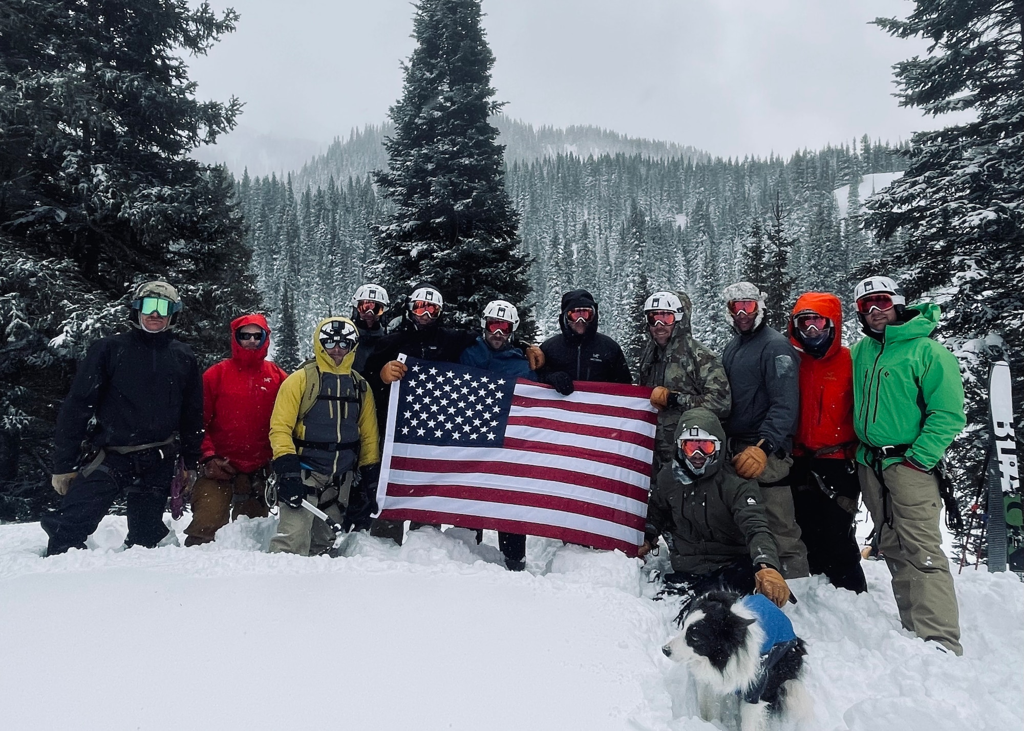 A group of men pose for a picture in the snow holding an American flag.
