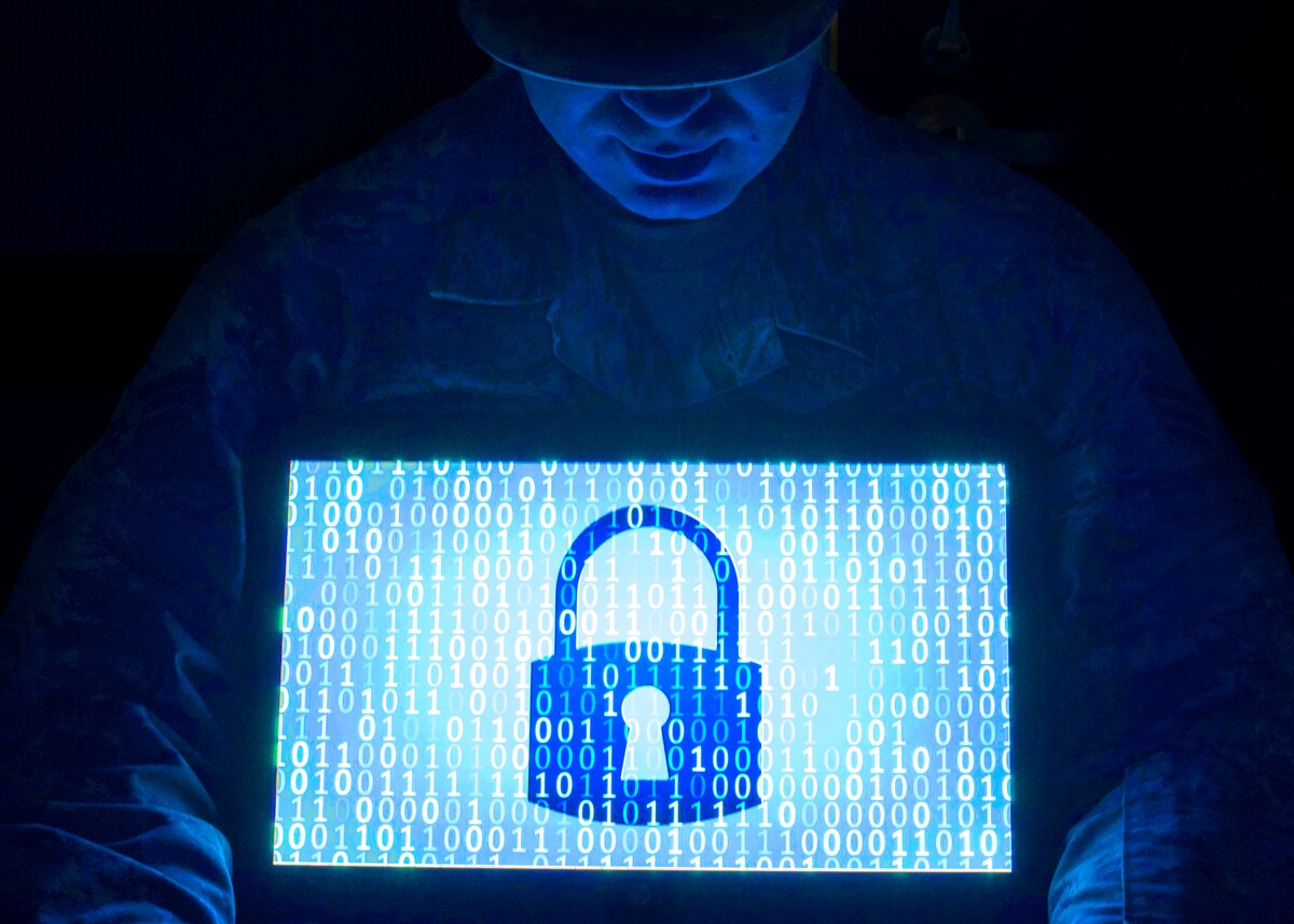 A man looks down on a computer screen that displays zeros and ones and a padlock.