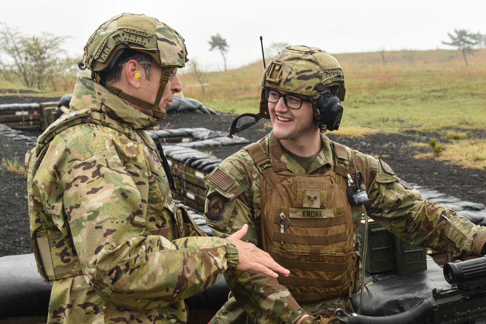 U.S. military personnel speak with each other on an outdoor firing range.