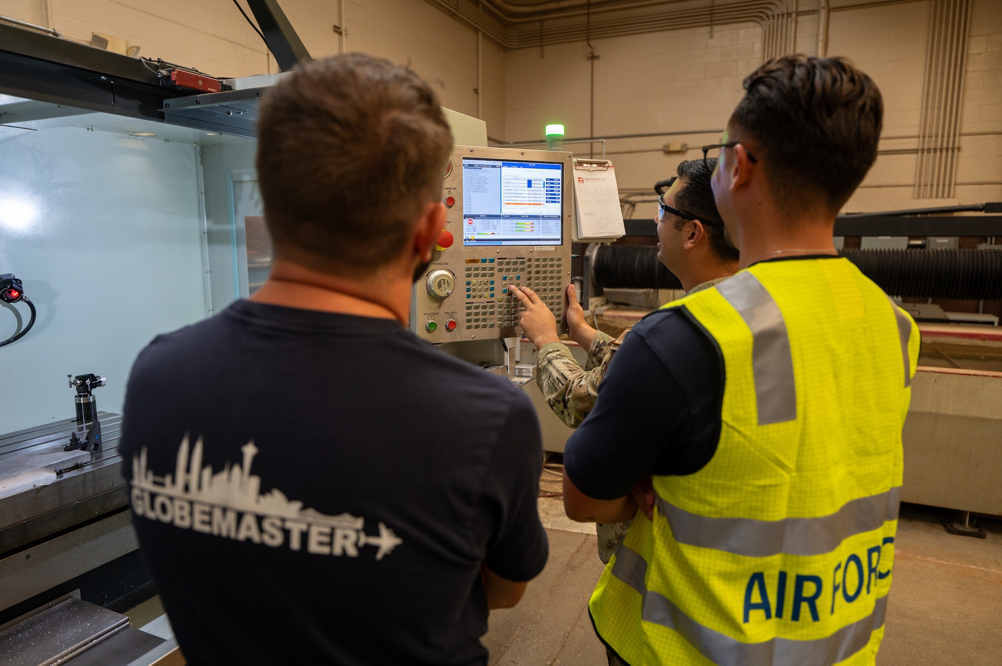 Airman shows Royal Australian Air Force members a device used in aircraft sheet metal.