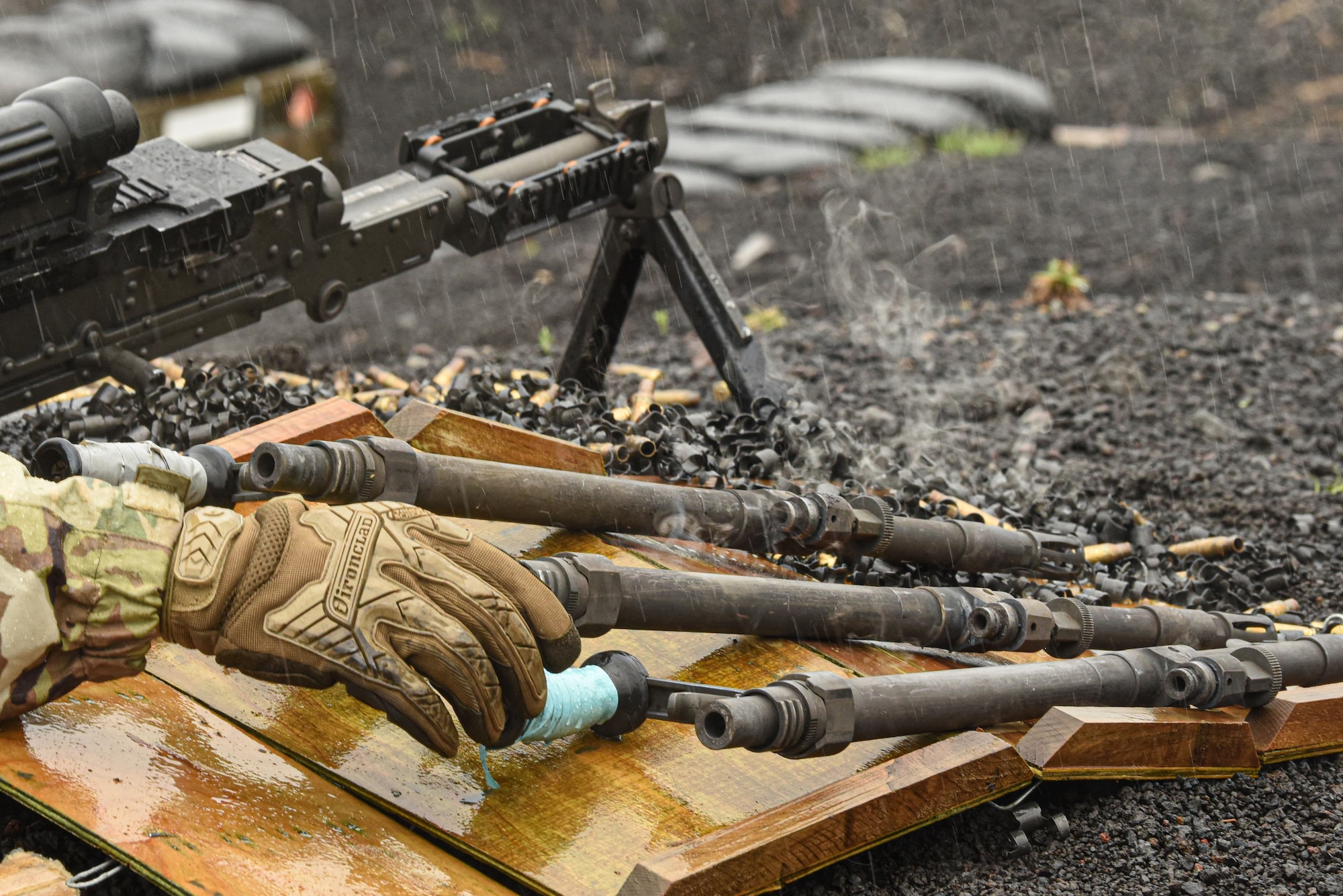 The steaming barrel of a machine gun is taken off and placed to the side.