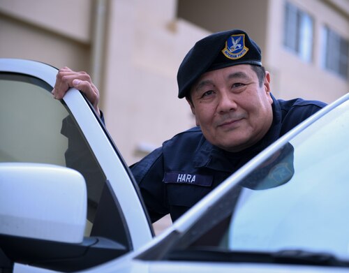A Japanese civilian guard poses next to a patrol car.