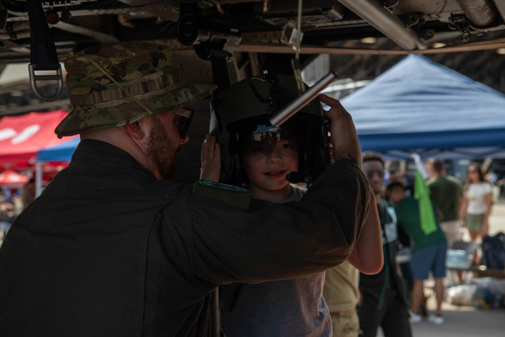 A festival attendee dons a helmet inside of a 33rd Rescue Squadron HH-60 Pave Hawk static display during America Fest 2024 at Kadena Air Base, Japan, April 27, 2024.