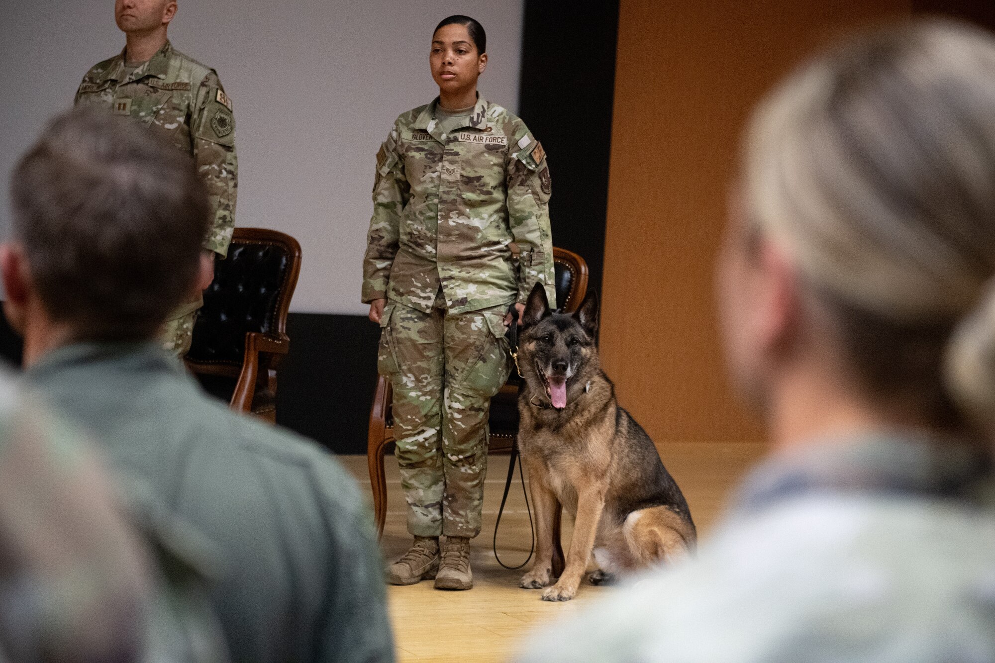 U. S. Air Force Staff Sgt. Ivana Glover, 39th Security Forces Squadron military working dog handler, stands at attention with MWD Brix on stage.