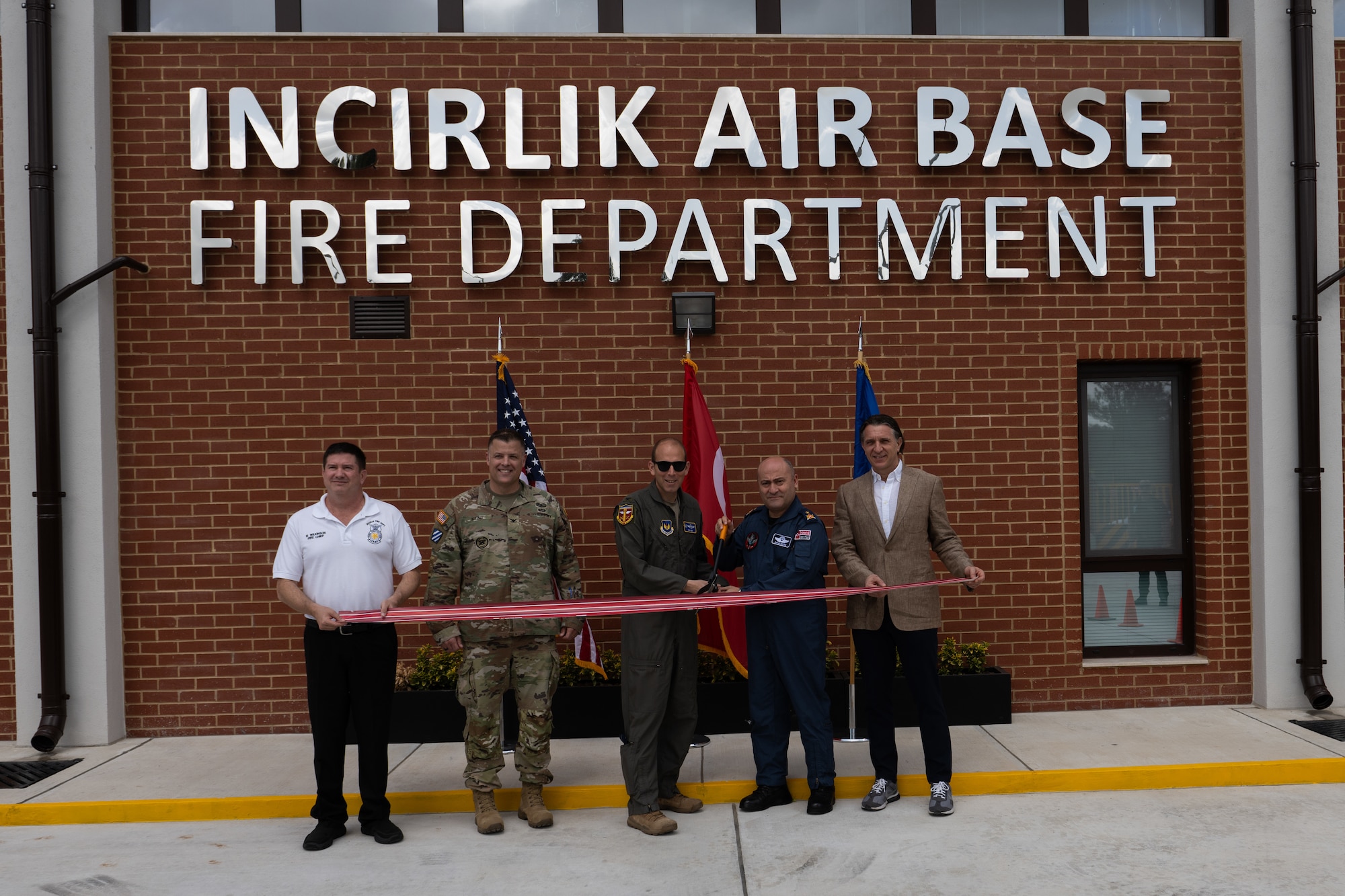 U.S. Air Force Col. Kevin Lord, 39 ABW commander, Turkish Air Force Brig. Gen. Kemel Güleç, 10th Main Jet Base Command commander  and Mehmet Aytekin, Aytekin Serol Cons Inc. company partner, pose for a photo holding a ribbon and a giant large pair of scissors.