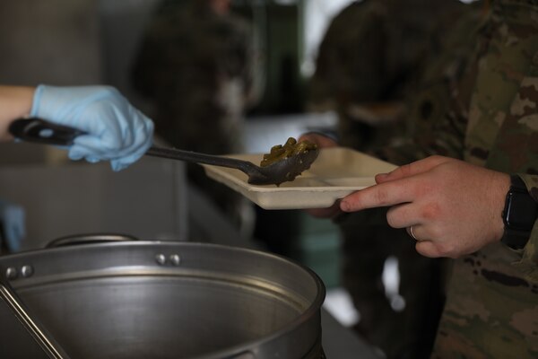 An Oklahoma Army National Guard cook and culinary specialist serves food to a Guardsman during the inaugural OKARNG Culinary Excellence Challenge at Camp Gruber Training Center, April 27, 2024. The OKARNG hosted its inaugural state-level culinary competition to bring Soldiers together to demonstrate their proficiency in a variety of culinary tasks and drills, fostering a culture of esprit de corps, resiliency, and personal growth for OKARNG Culinary Specialists. (Oklahoma National Guard photo by Sgt. Elliott Kim)