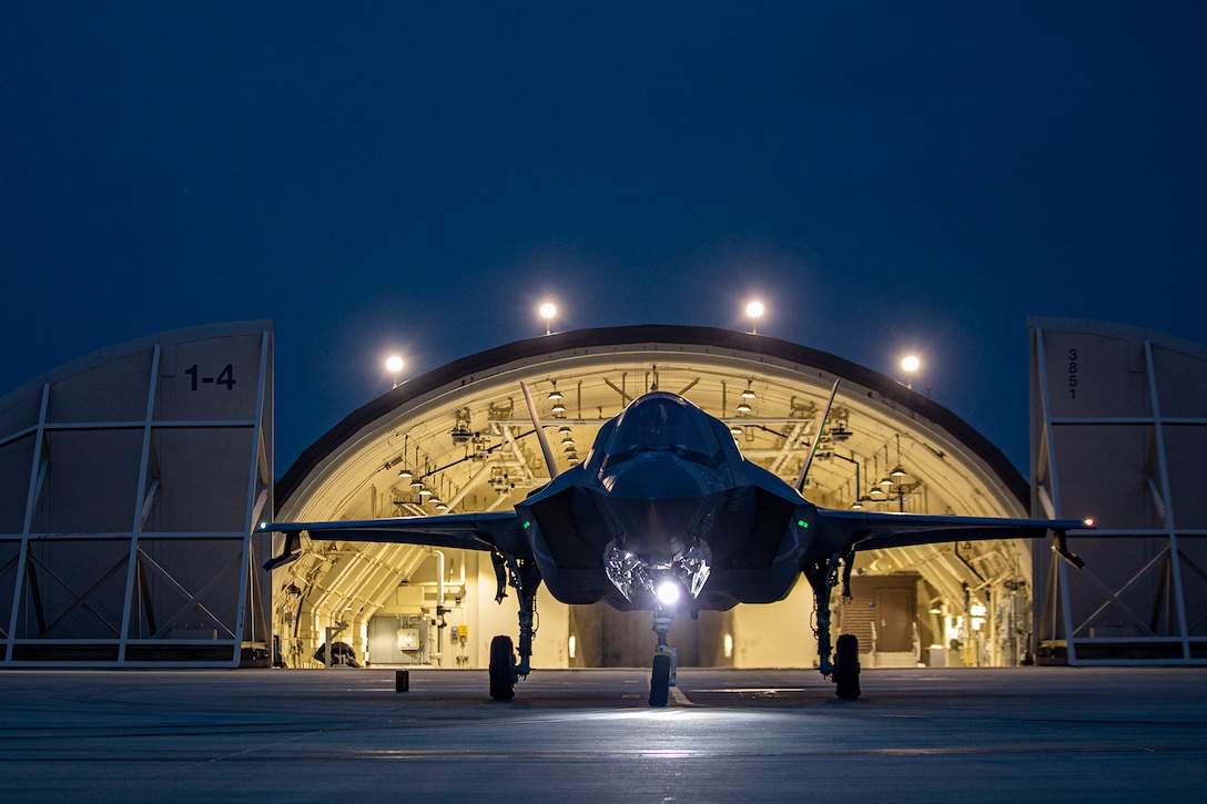 A military aircraft is parked on the tarmac at twilight.