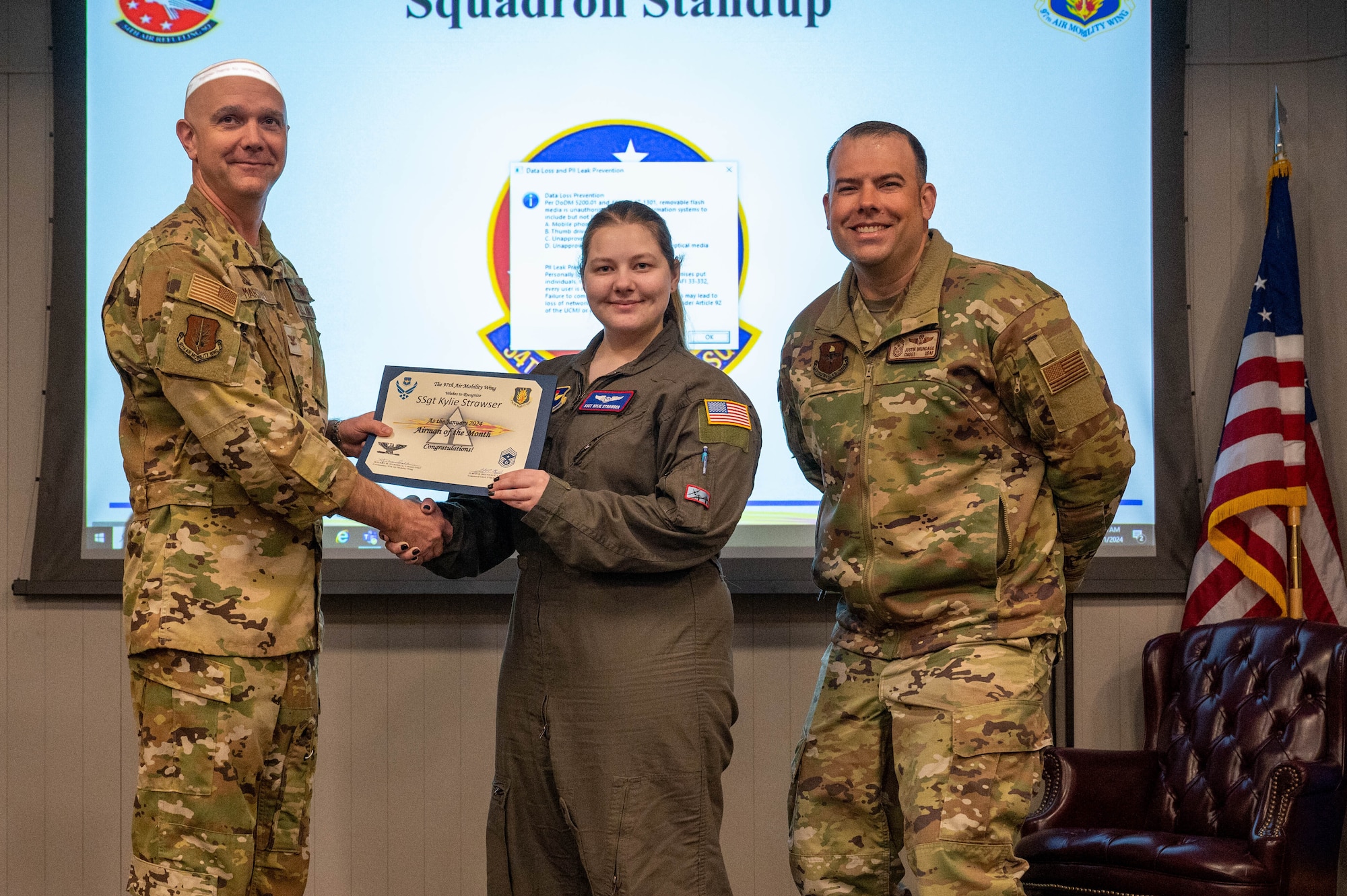 U.S. Air Force Staff Sgt. Kylie Strawser, 54th Air Refueling Squadron boom operator instructor, center, is named the January 2024 Airman of the Month by Col. Jeff Marshall, 97th Air Mobility Wing (AMW) commander, left, and Chief Master Sgt. Justin Brundage, 97th AMW command chief, right, at Altus Air Force Base, Oklahoma, March 11, 2024. When she’s not teaching new students on the KC-135 Stratotanker aircraft, Strawser is the unit’s suicide prevention implementor, where she provides training and support throughout her squadron. (U.S. Air Force photo by Airman 1st Class Heidi Bucins)