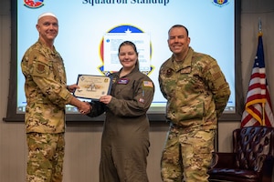 U.S. Air Force Staff Sgt. Kylie Strawser, 54th Air Refueling Squadron boom operator instructor, center, is named the January 2024 Airman of the Month by Col. Jeff Marshall, 97th Air Mobility Wing (AMW) commander, left, and Chief Master Sgt. Justin Brundage, 97th AMW command chief, right, at Altus Air Force Base, Oklahoma, March 11, 2024. When she’s not teaching new students on the KC-135 Stratotanker aircraft, Strawser is the unit’s suicide prevention implementor, where she provides training and support throughout her squadron. (U.S. Air Force photo by Airman 1st Class Heidi Bucins)