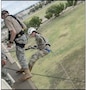 Female cadet in Army uniform reppelling off a rappel tower