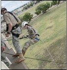 Female cadet in Army uniform reppelling off a rappel tower