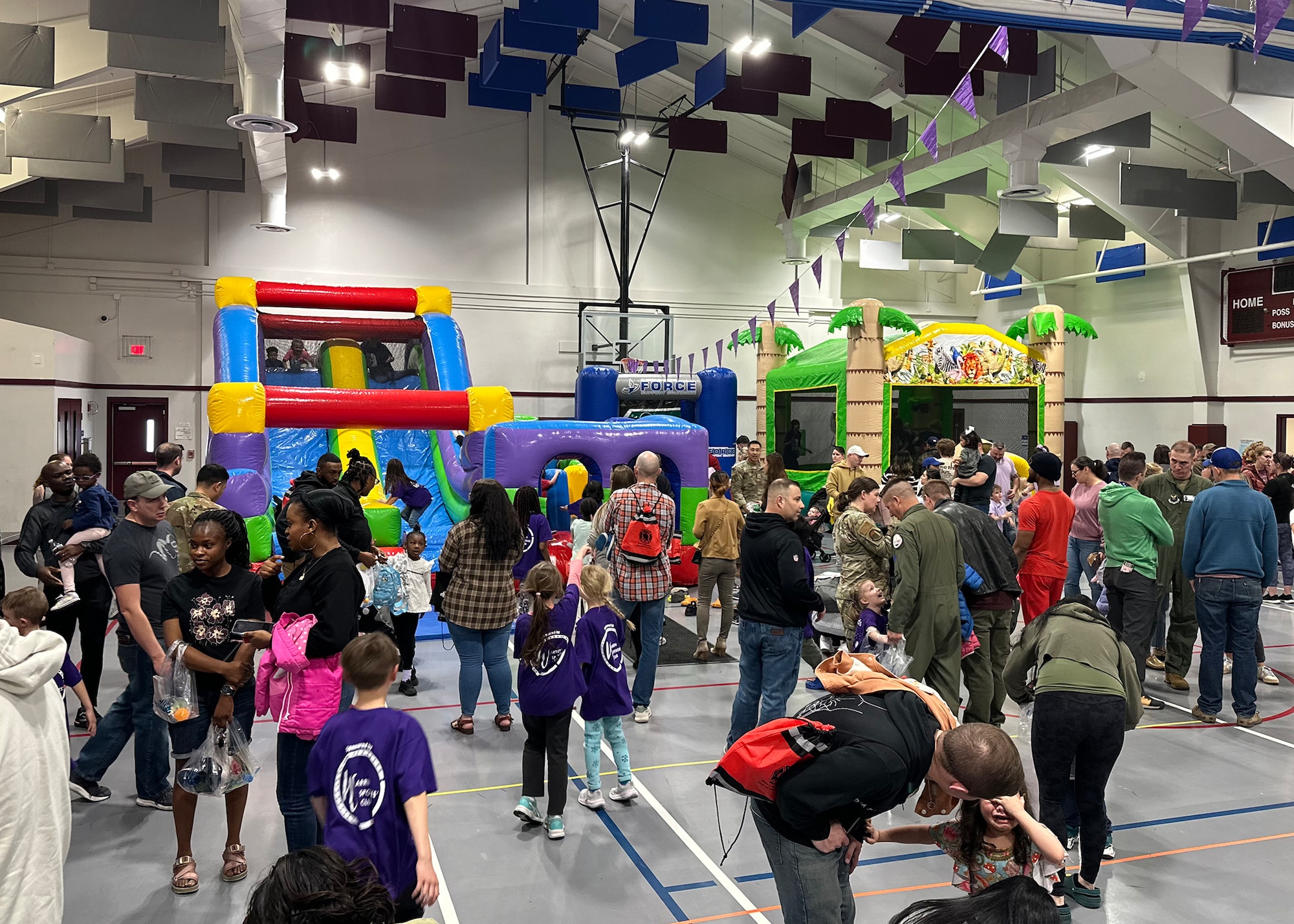 group of people on a court, with inflatable slides and bounce houses