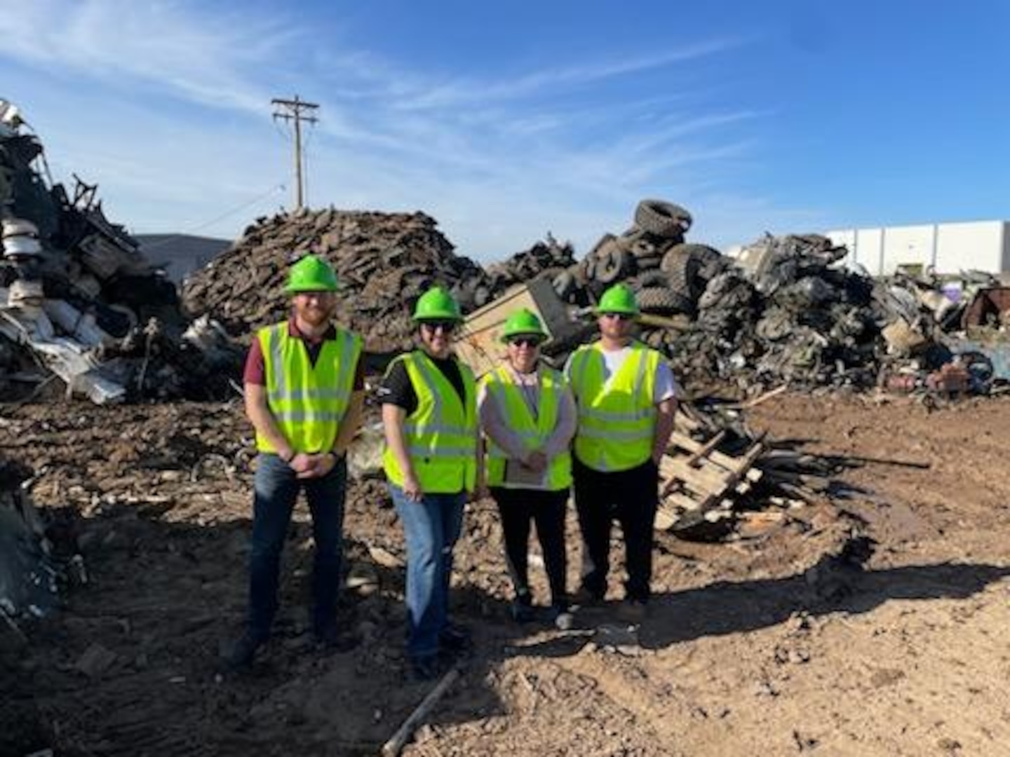 group poses in a scrap yard