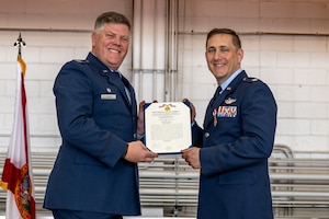 U.S. Air Force Col. Adam E. Moore, the 1st Special Operations Group commander, left, presents the Meritorious Service Medal certificate to Lt. Col. Matthew Slack, the 319th Special Operations Squadron’s outgoing commander, during the 319th SOS change of command and reassignment ceremony at Hurlburt Field, Florida, May 3, 2024. The reassignment of the 319th SOS from the 1st Special Operations Wing to the 492d Special Operations Wing is part of a greater initiative by Air Force Special Operations Command to ensure units can rapidly deploy and sustain power in support of the National Defense Strategy. (U.S. Air Force photo by Senior Airman Hussein Enaya)