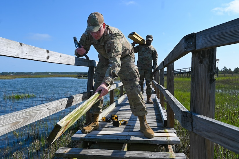 U.S. Air Force Airman 1st Class Luke Milanian, left, and Airman 1st Class Khylon Rawls, 633d Civil Engineering Squadron electrical systems journeymen, replace worn out boards on the Nature Walk at Joint Base Langley-Eustis, Virginia, April 26, 2024. Annual maintenance is performed at the Nature Walk to keep the boardwalk safe for the marsh wildlife area. (U.S. Air Force photo by Airman 1st Class Skylar Ellis)