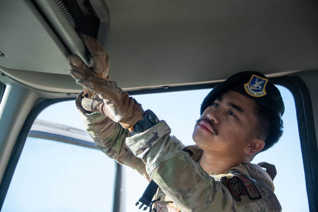 A Security Forces defender inspects the cab of a truck.