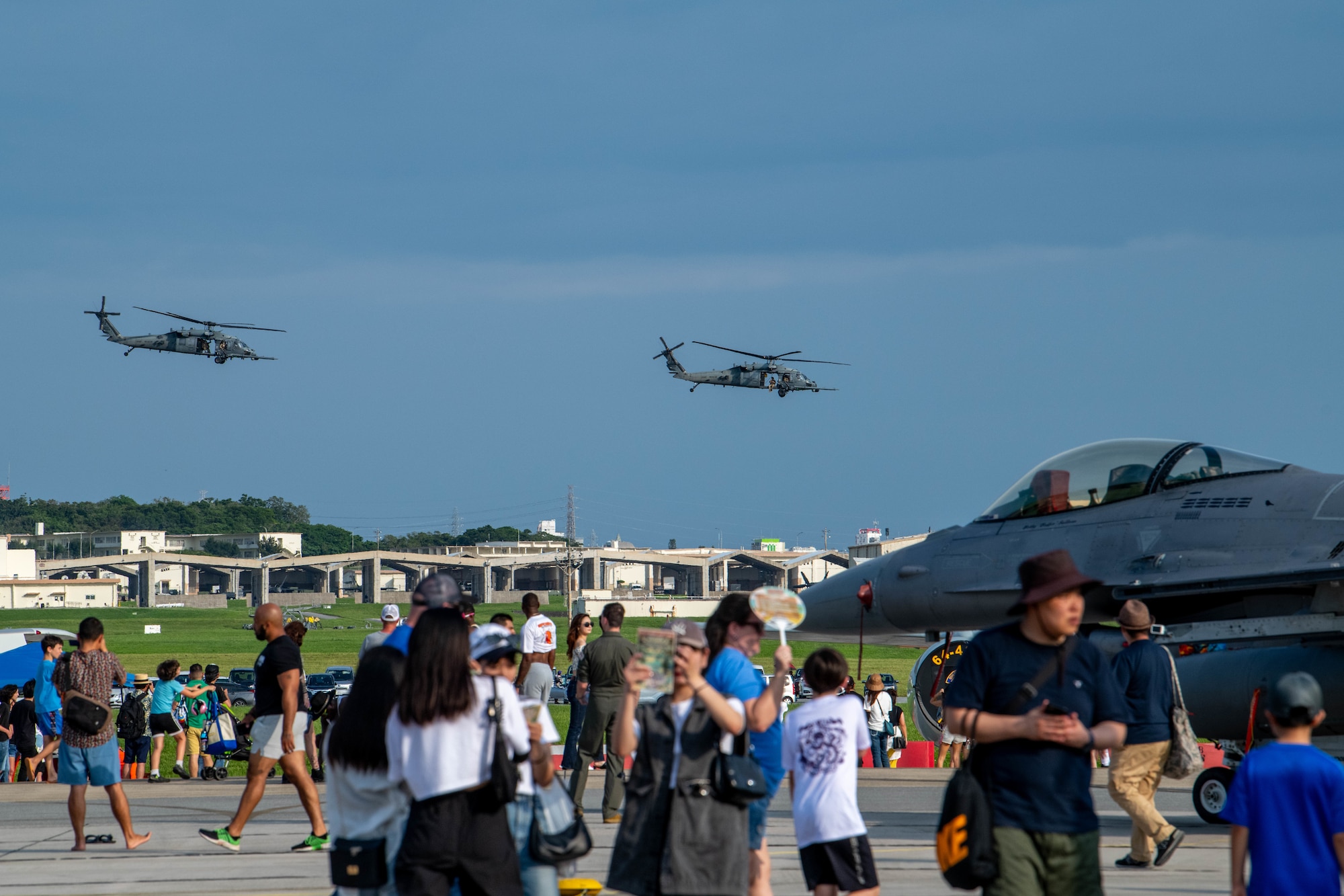 Festival attendees observe HH-60 Pave Hawks assigned to the 33rd Rescue Squadron conduct a training flight, during America Fest 2024, at Kadena Air Base, Japan, April 27, 2024.