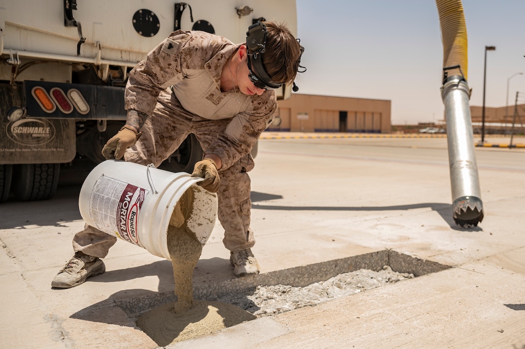 A U.S. Marine Corps combat engineer assigned to the 2nd Marine Logistics Group pours concrete to repair the flightline at an undisclosed location within the U.S. Central Command area of responsibility, May 4, 2024. The Airmen and Marines came together to improve operation resilience and share best practices. (U.S. Air Force photo)