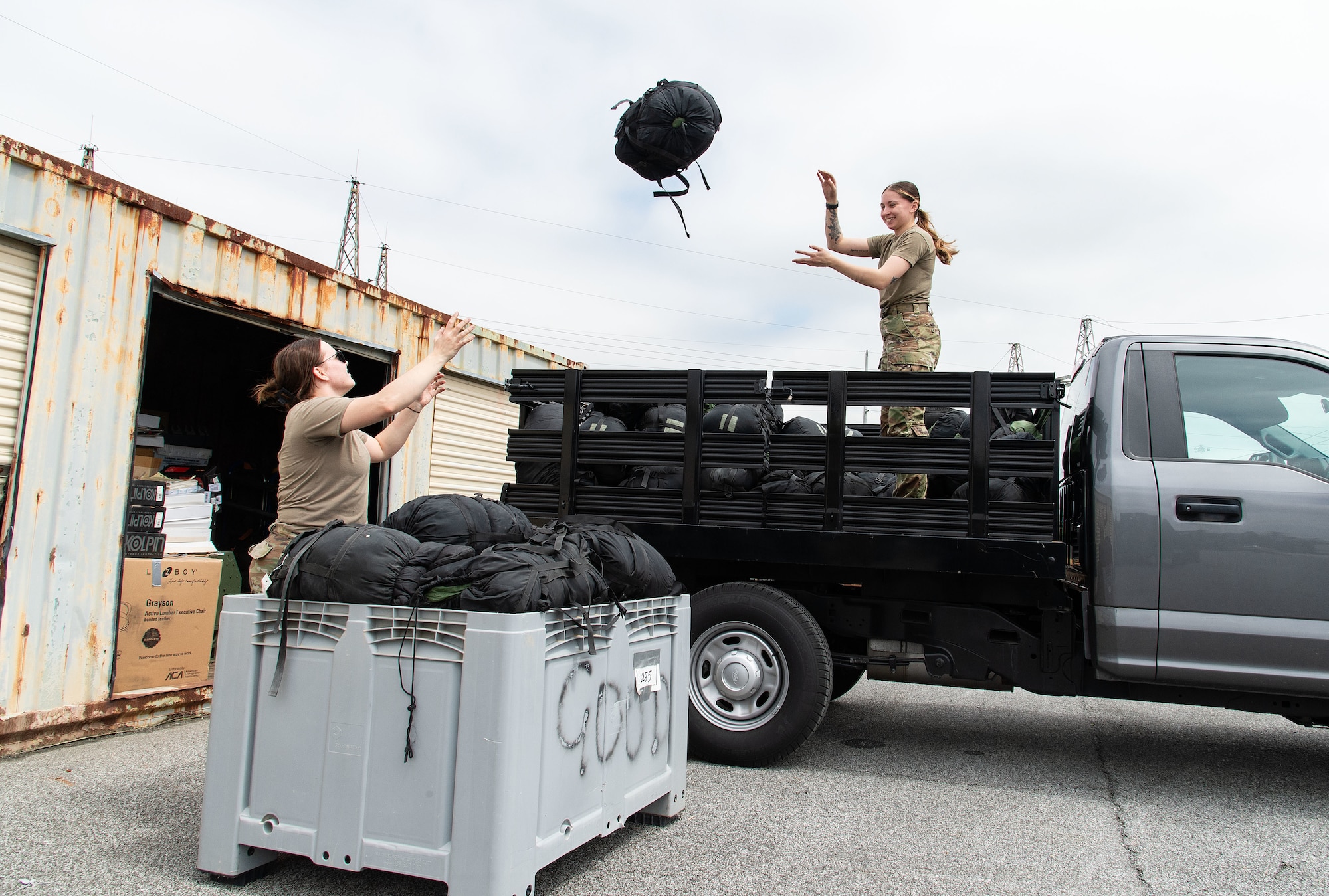 U.S. Air Force Senior Airman Lindsay Wells, right, 436th Security Forces Squadron vehicle control officer, tosses a sleeping bag to Staff Sgt. Amanda Long, left, 436th SFS supply noncommissioned officer in charge, during the Recycling Center Open House at Dover Air Force Base, Delaware, April 18, 2024. Squadrons from across the base turned in unwanted or excess items to the center for proper disposition. (U.S. Air Force photo by Roland Balik)