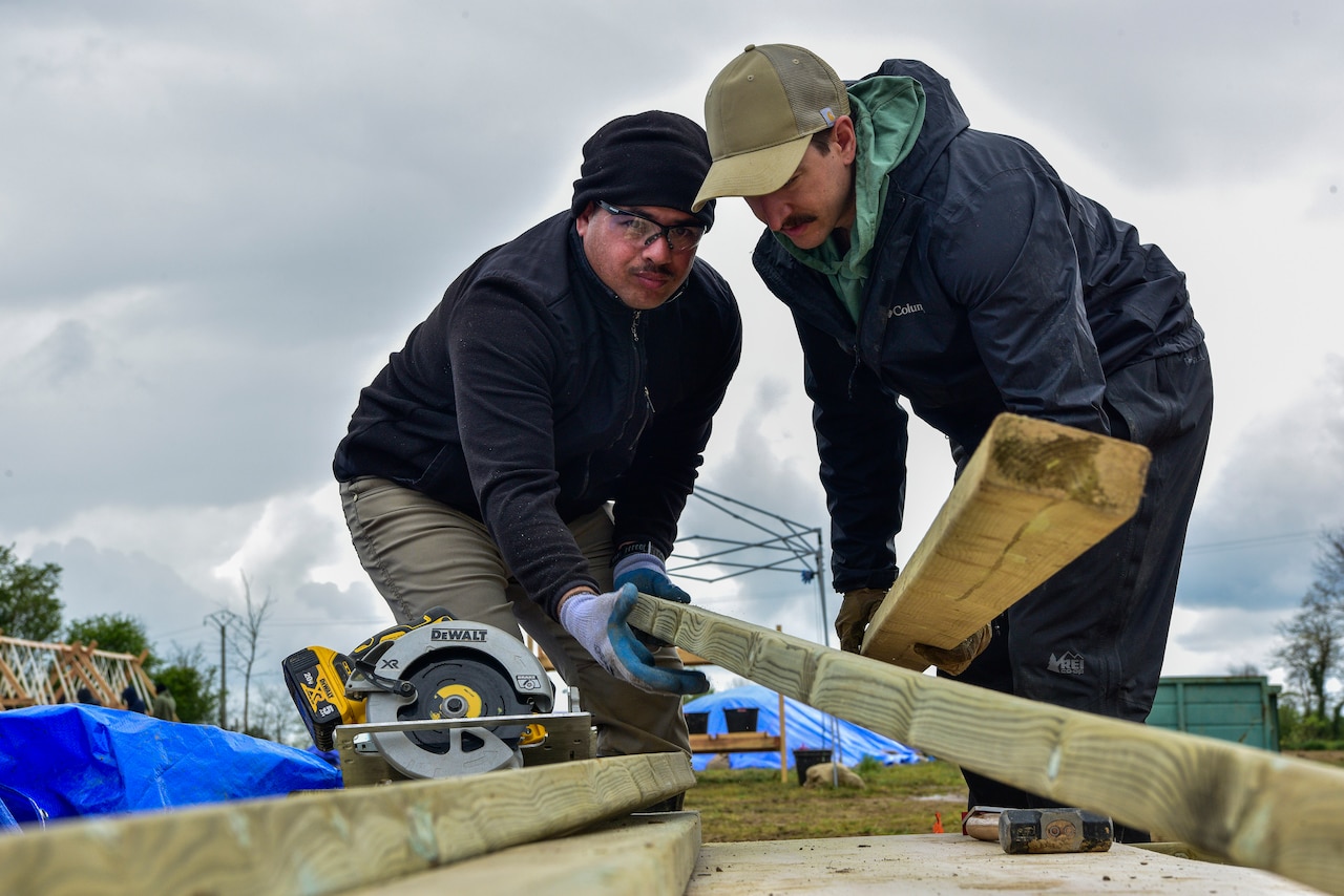Two people build a wood structure.