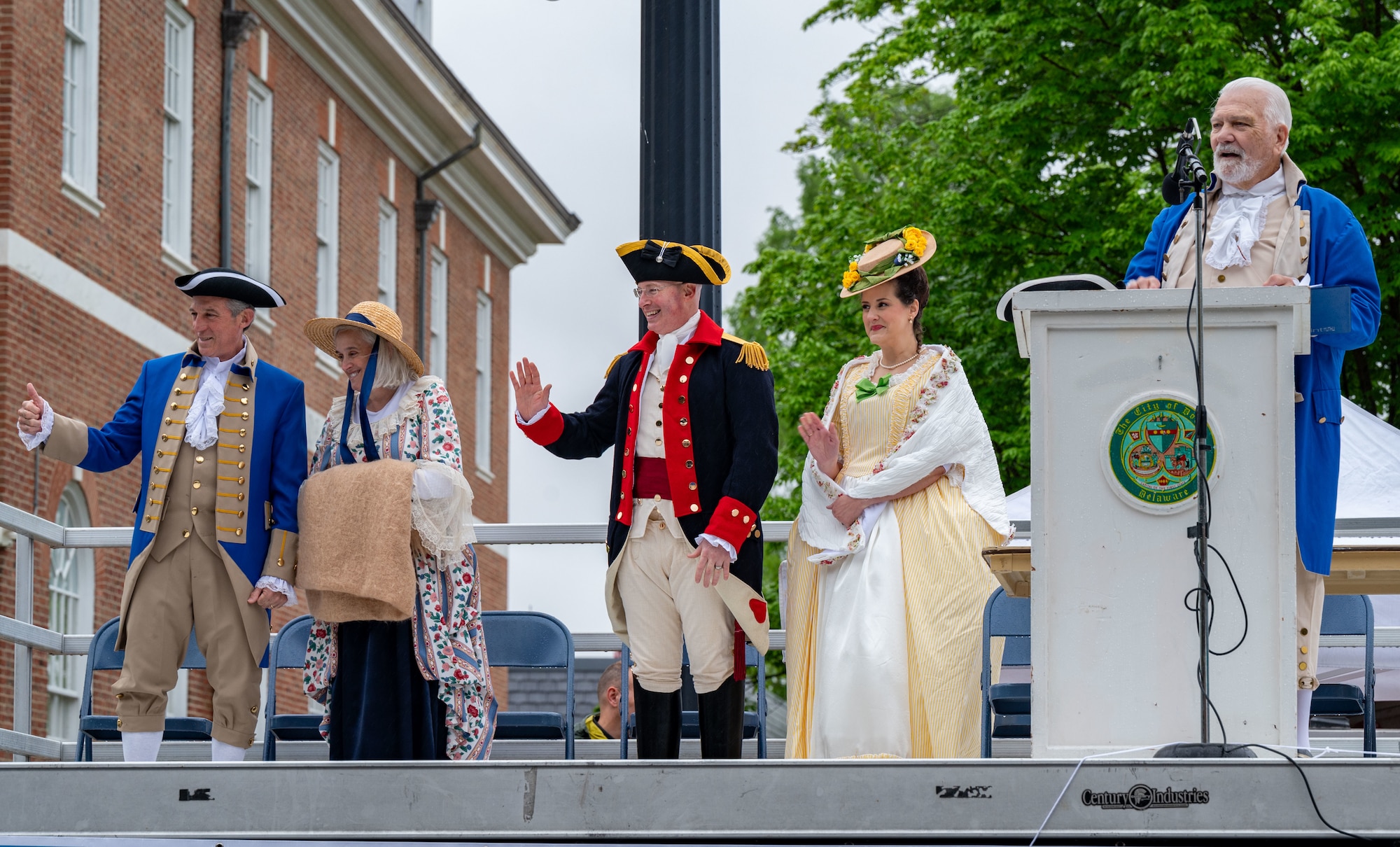 U.S. Air Force Col. Chris McDonald, center, 436th Airlift Wing commander, and his wife, Diana McDonald, wave to parade participants in Dover, Delaware, May 4, 2024. The McDonald’s dressed in colonial attire for the 91st Annual Dover Days Festival and Parade, an event that highlights the First State’s history and heritage. (U.S. Air Force photo by Airman 1st Class Amanda Jett)