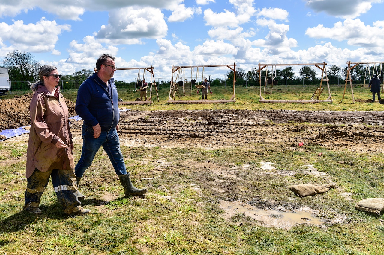 Two people walk side-by-side at an excavation site.