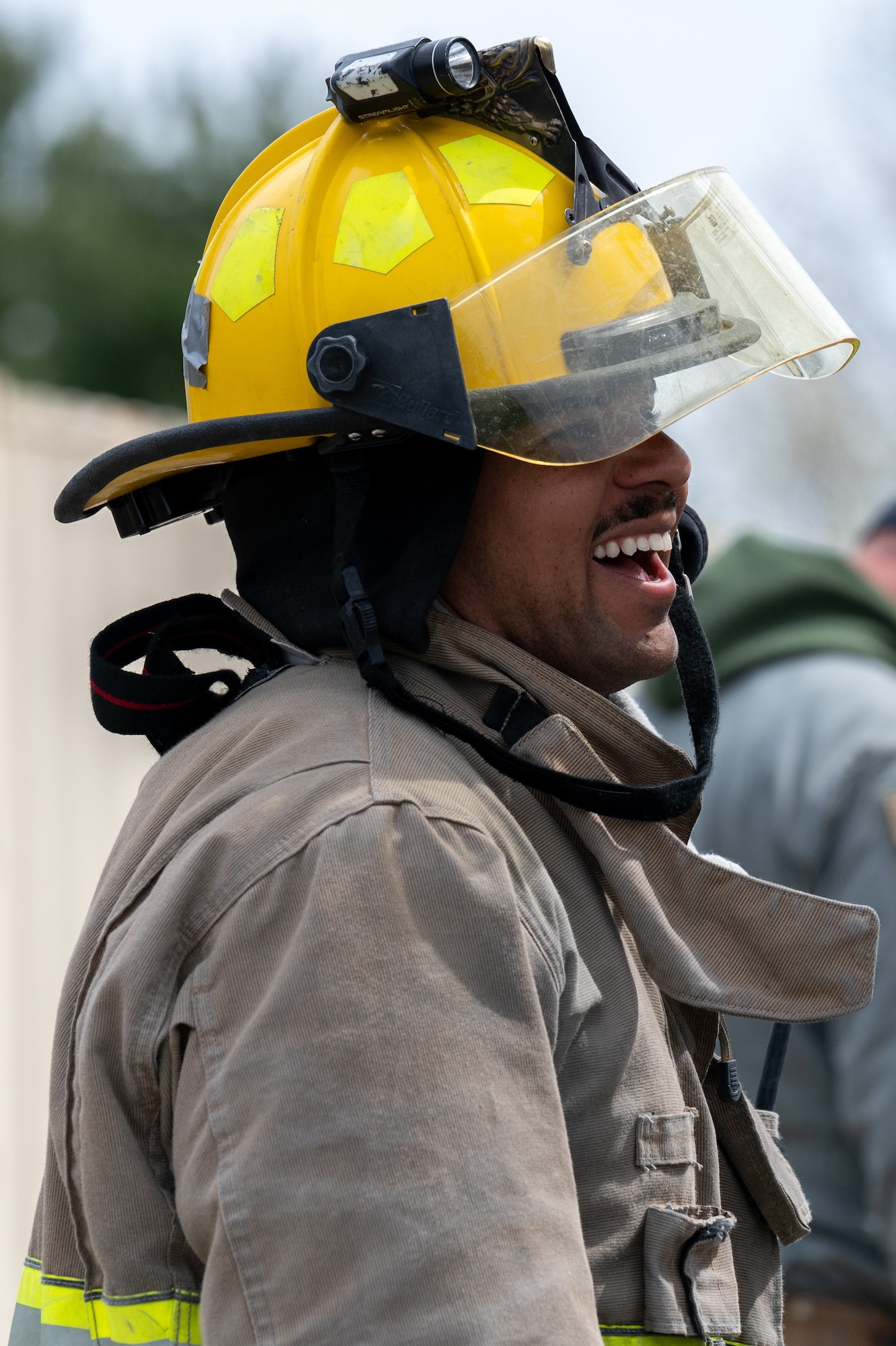 A firefighter, uniformed, laughs.