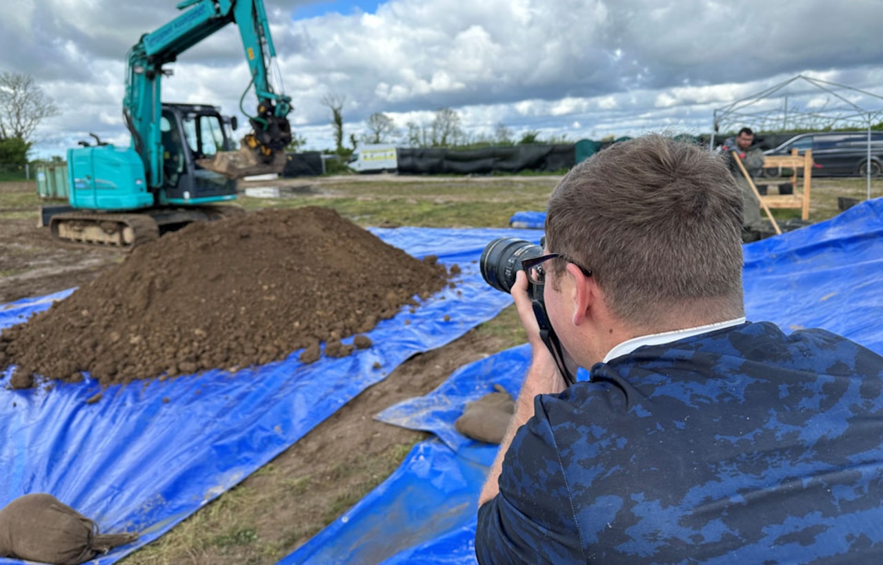 A man photographs an excavation site.