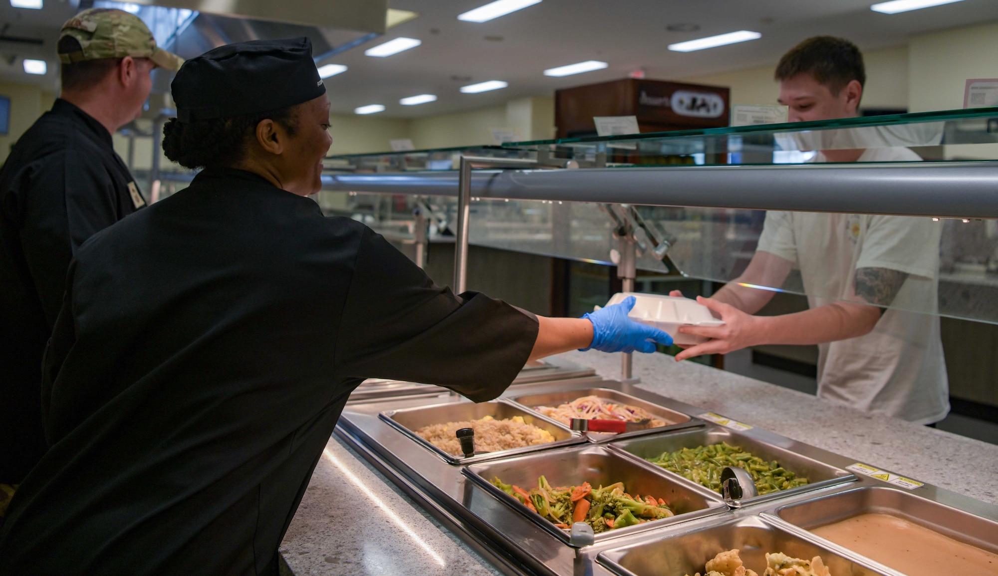 U.S. Air Force Chief Master Sgt. Jennell Chalk, 18th Wing Staff Agencies senior enlisted leader, serves food to an Airman at the Marshall DFAC to celebrate its reopening at Kadena Air Base, Japan, May 6, 2024.