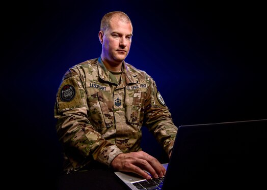  U.S. Space Force Master Sgt. Stephen Lescroart poses for a photo with a laptop.